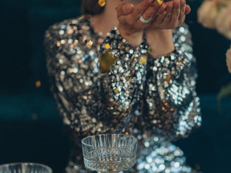 A woman in a sequin dress blowing confetti
