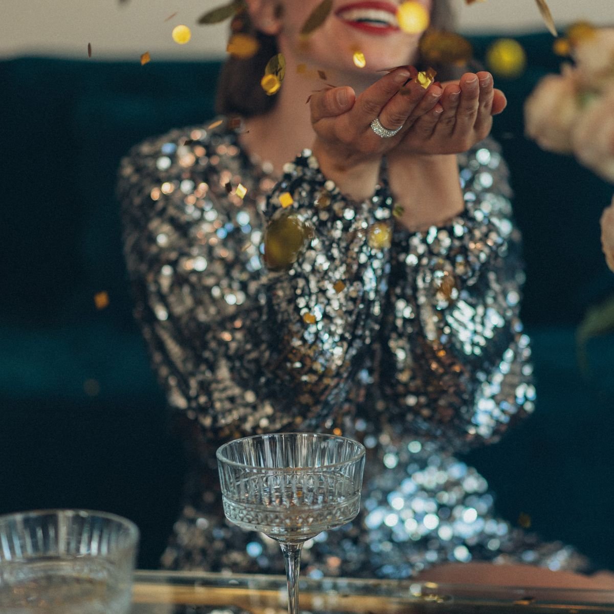 A woman in a sequin dress blowing confetti