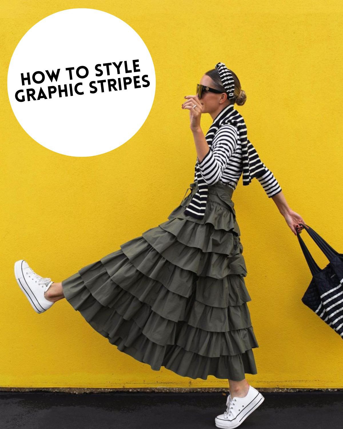 A woman wearing several different striped pieces standing in front of a yellow wall