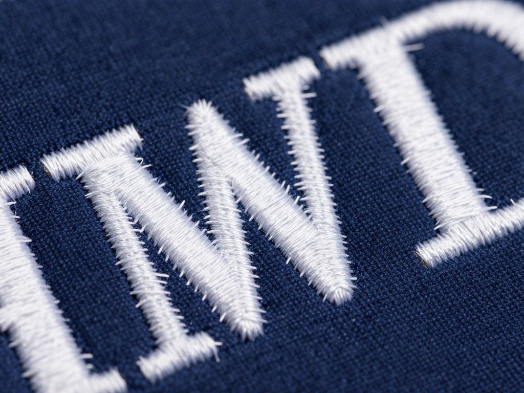 Dimensional raised satin stitch embroidery letters showing padded technique with multiple thread layers