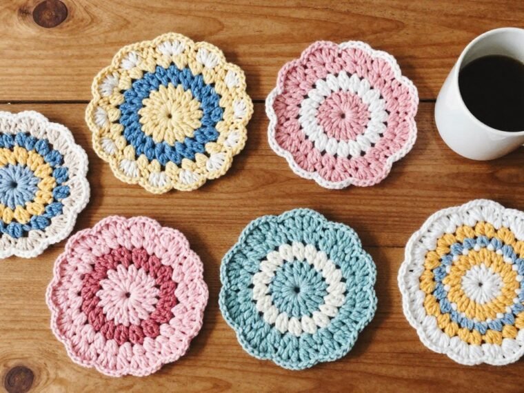 colorful crochet coasters displayed on wooden table with coffee mug