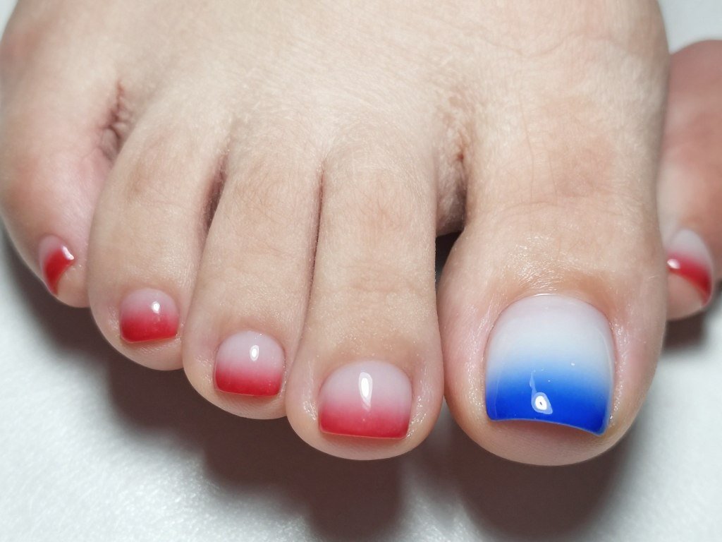 Gradient toe nails transitioning from red at base through white to blue at tips