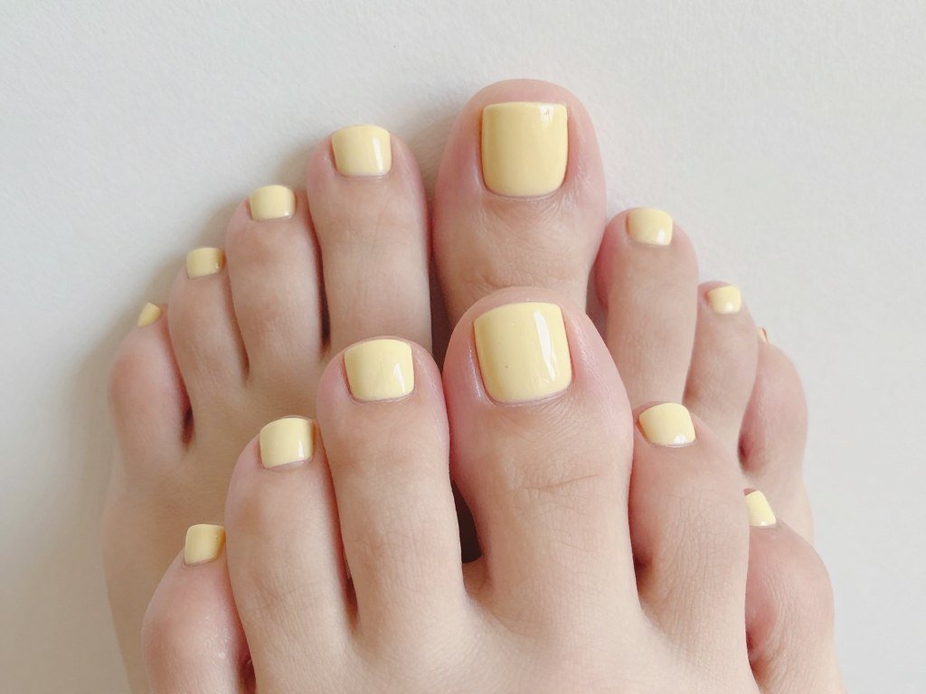 Butter yellow trending nail color on optimistic summer pedicure