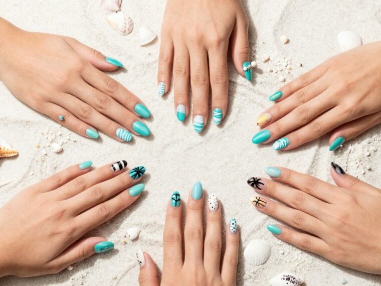 Collection of summer beach nail designs featuring ocean colors, seashells, and tropical patterns on manicured hands against beach background